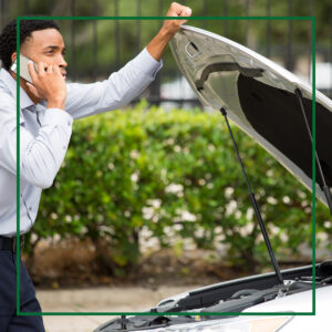 oung man on the phone with an agent, standing in front of his car with the hood popped open.