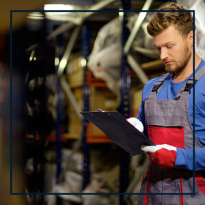 Man in technician uniform checking inventory on a clipboard.